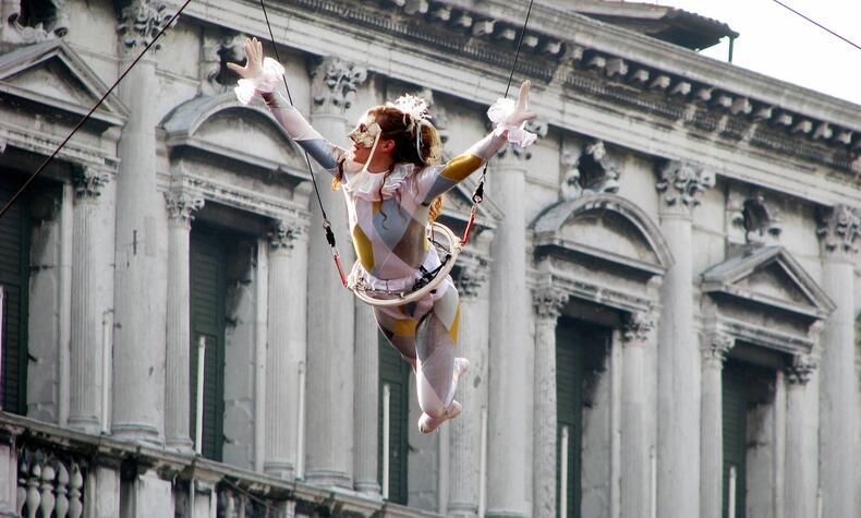A female acrobat throws herself suspended from the top of the Campanile into St. Mark's Square. carnival venice volo angelo